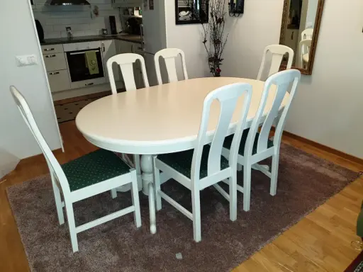 Vitt runt matbord med sex stolar med gröna dynor. Perfekt för att lacka om stolar och ge dem nytt liv.