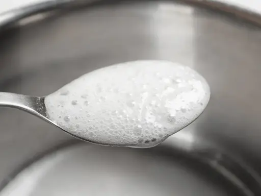 En sked med skummande bikarbonat utan aluminium, redo att användas för rengöring eller bakning.