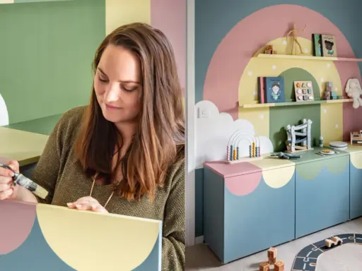 Kvinna målar hyllplan i pastellfärger för ett lekfullt barnrum. En regnbågsdesign pryder väggen och möblerna.