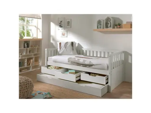 Vit barnsäng med förvaring i form av lådor under. Sängen har en vit sänghimmel och en kudde med fjäderprint.