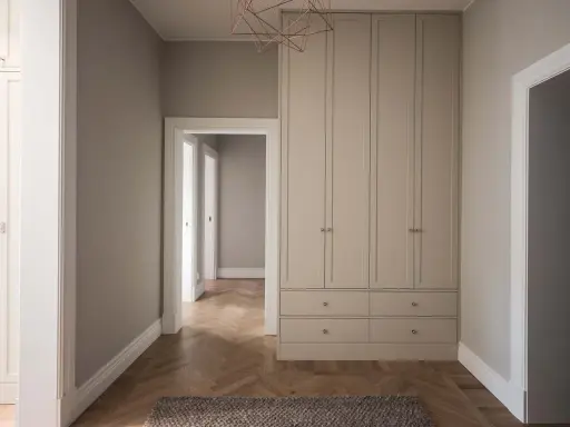 En hall med en stor garderob i ljusgrått och fiskbensparkett. Perfekt grå hall inspiration för ett modernt hem.