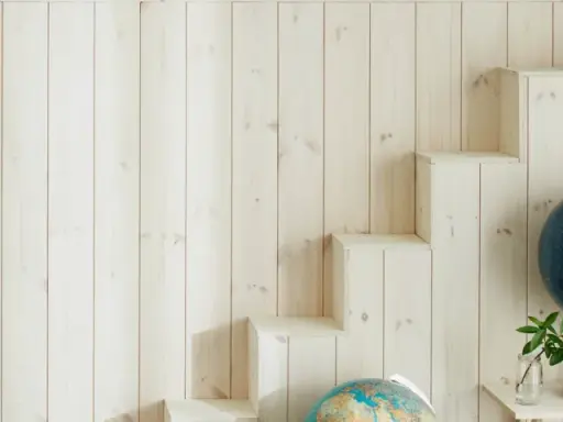 En vägg med ljus träpanel ger en mysig känsla. En gammal sjökarta hänger på ena sidan, medan en trappliknande hylla på andra sidan visar upp jordglober och böcker. Perfekt panel inomhus inspiration för äventyrliga själar.