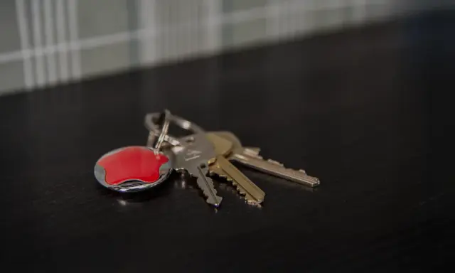 Nycklar med en röd Verisure-tagg. Tänk på hur larmar man på Verisure när du lämnar hemmet.