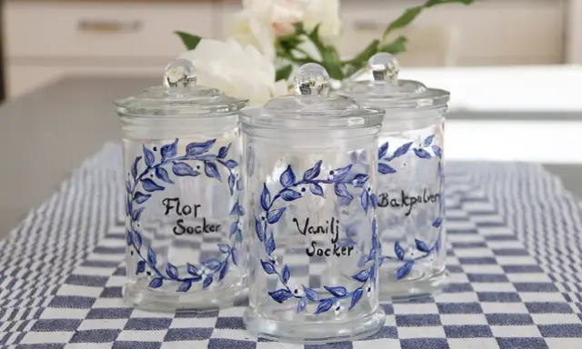 Tre vackra glasburkar med blå blommotiv, perfekta för att måla på glasburkar och förvara socker eller bakpulver.