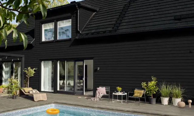 Ett modernt svart hus med pool och uteplats. Perfekt för att måla i solsken och njuta av sommaren.