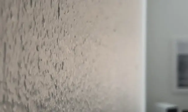 Närbild på en vägg där man har bredspacklat på tapet. Ytan är ojämn och texturerad.