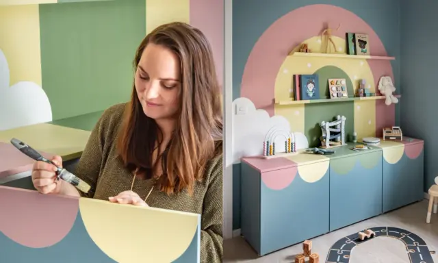 Kvinna målar hyllplan i pastellfärger för ett lekfullt barnrum. En regnbågsdesign pryder väggen och möblerna.