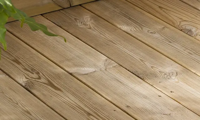 Träaltanen behöver behandlas för att behålla sin lyster. Gröna blad skymtar i övre vänstra hörnet.