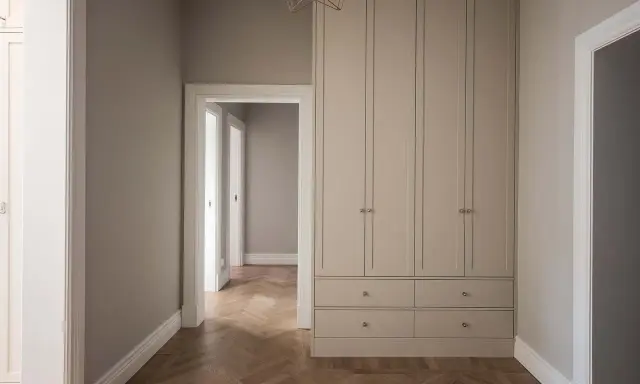 En hall med en stor garderob i ljusgrått och fiskbensparkett. Perfekt grå hall inspiration för ett modernt hem.