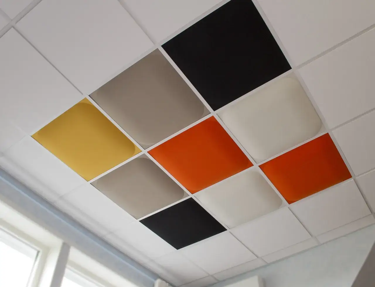 Färgglada innertak plattor i gult, orange, grått och svart blandas med vita. En modern lösning för att måla innertak plattor.