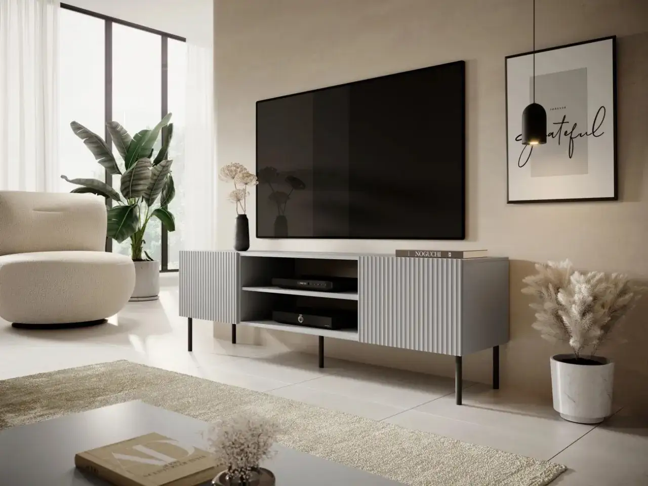 En modern tv konsol i grått med ribbade fronter, placerad under en stor TV. En bekväm fåtölj och en stor grön växt bidrar till den stilrena inredningen.