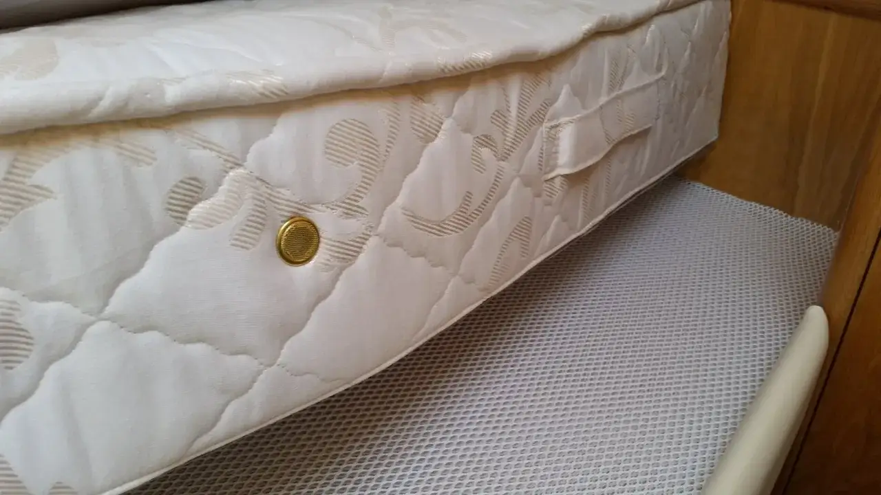 En vit madrass med mönster ligger på en vit, nätliknande matta. Perfekt madrass förvaring i en husvagn eller båt.