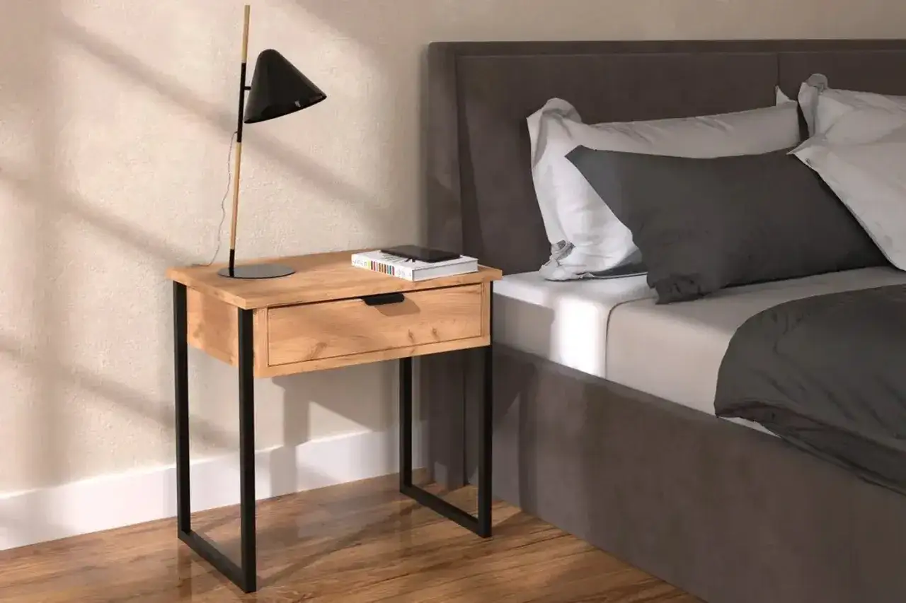 S&auml;ngbord i oljad ek med en svart lampa och en bok. Bredvid s&auml;ngen med gr&aring;a och vita kuddar.