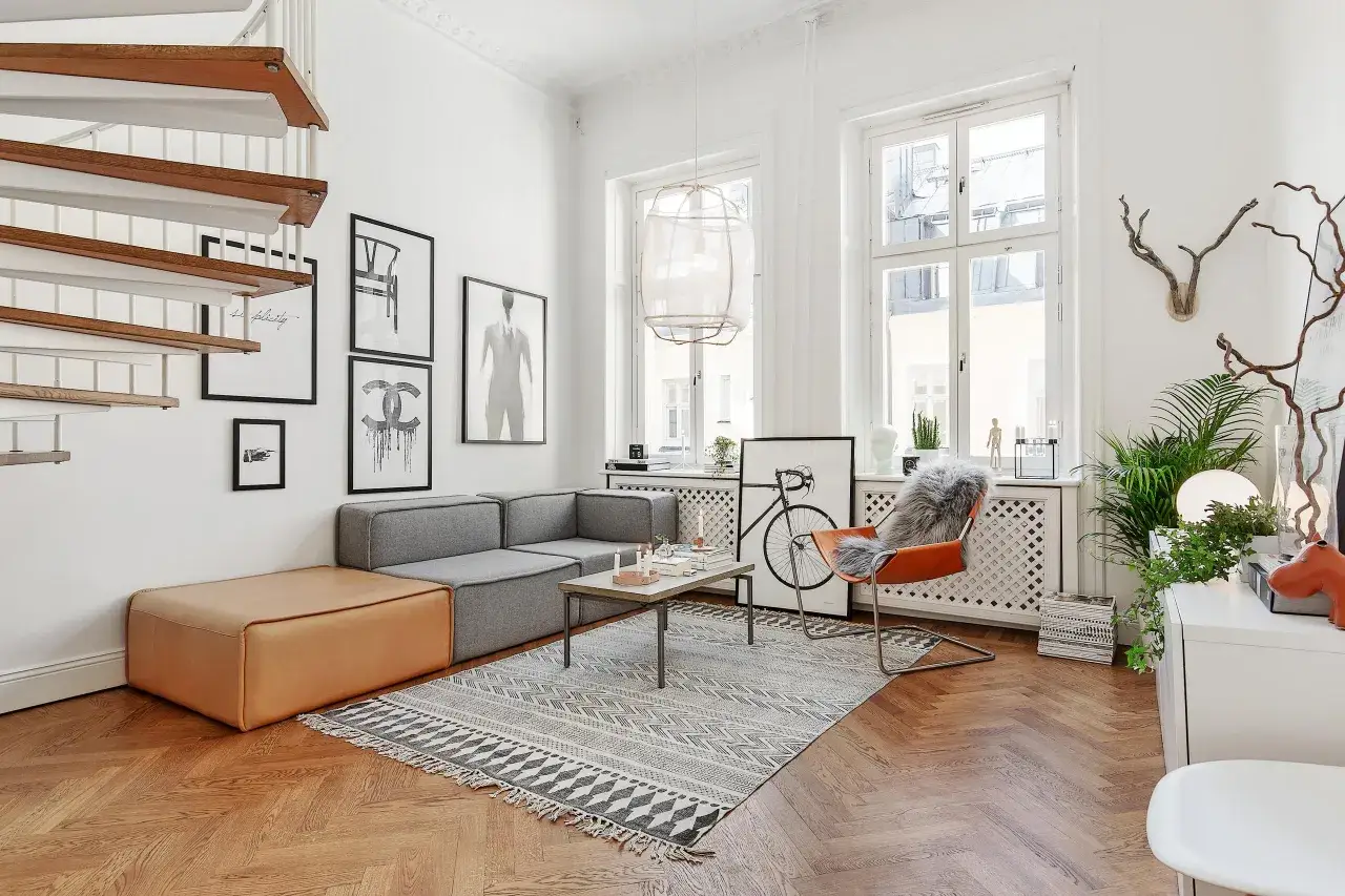 En ljus och luftig l&auml;genhet med en spiraltrappa, gr&aring; soffa, orange f&aring;t&ouml;lj och konst p&aring; v&auml;ggarna. Perfekt inspiration kontor f&ouml;r kreativa sj&auml;lar.