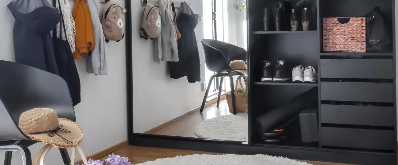 En liten hall med kl&auml;der och ryggs&auml;ckar p&aring; krokar, en stol med hatt och korg, samt en stor garderob med skor och f&ouml;rvaring. Perfekt f&ouml;r en barnfamilj.